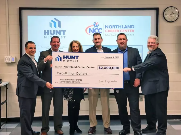 Six people in business attire hold a large ceremonial check for $2,000,000 made out to Northland Career Center from Hunt Midwest.
