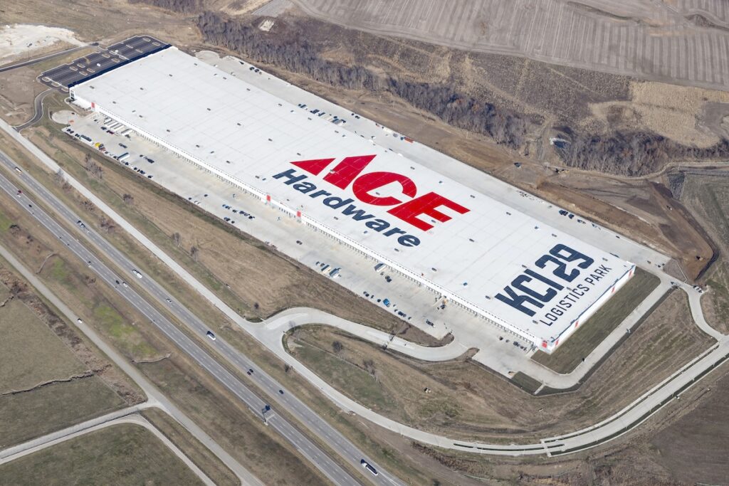 Large warehouse building with 'ACE Hardware' in red letters and 'KC 29 Logistics Park' painted on the roof, surrounded by roads and fields.