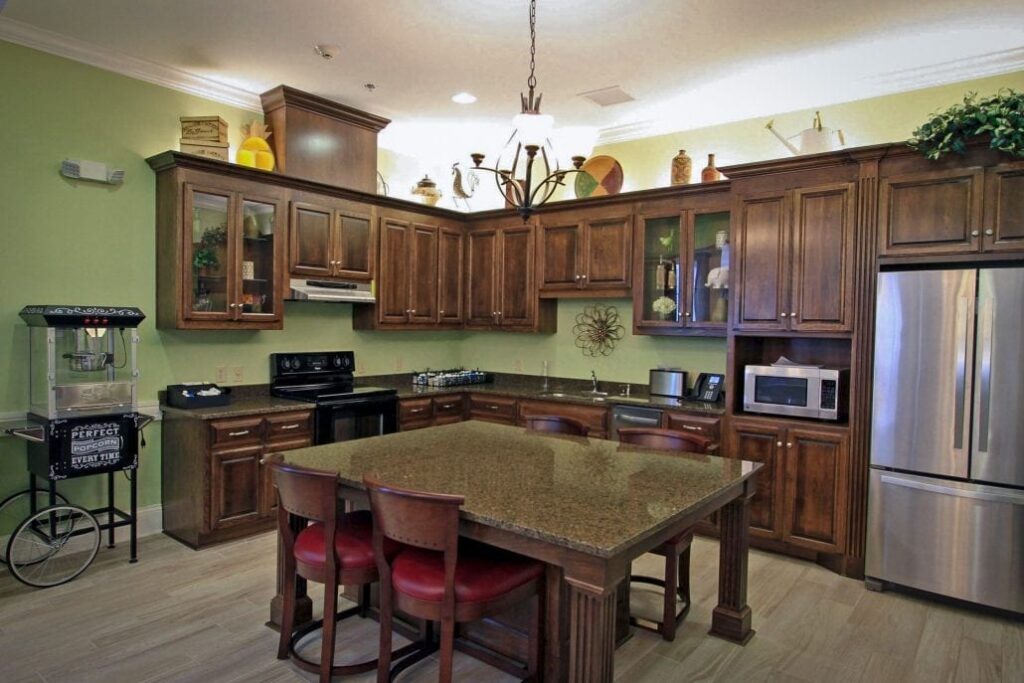 Spacious kitchen featuring dark wood cabinetry, stainless steel appliances, large island with seating, and decorative items above cabinets.