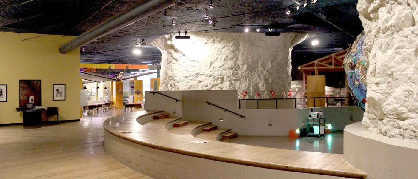 Modern office area built inside cave-like rock structure with wood floors, meeting tables, and lighting.